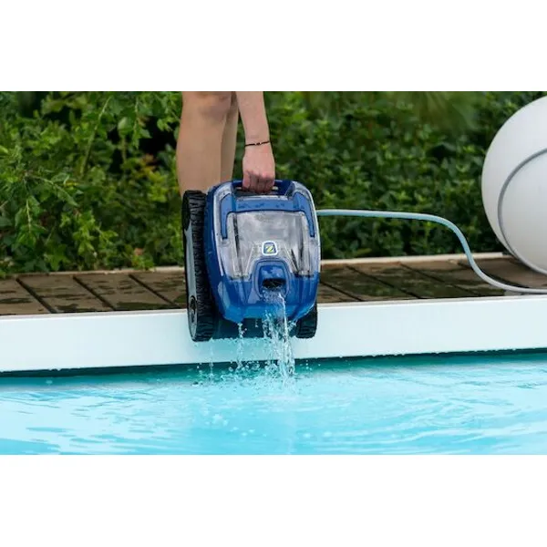 En person lyfter poolroboten Zodiac RT 3200 ur poolen, vatten droppar av vid poolkanten.